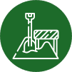 A white line drawing of a shovel stuck in a pile of dirt next to a striped barrier, all within a solid green circle.